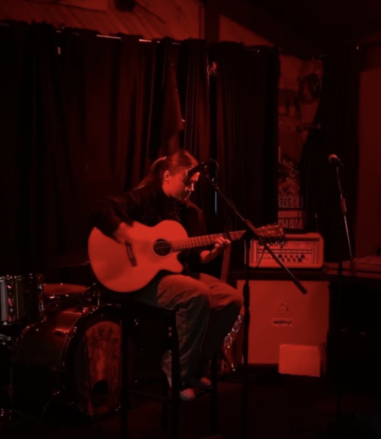 Ella performing guitar at an intimate red-lit bar at The Snow, Mount Hotham